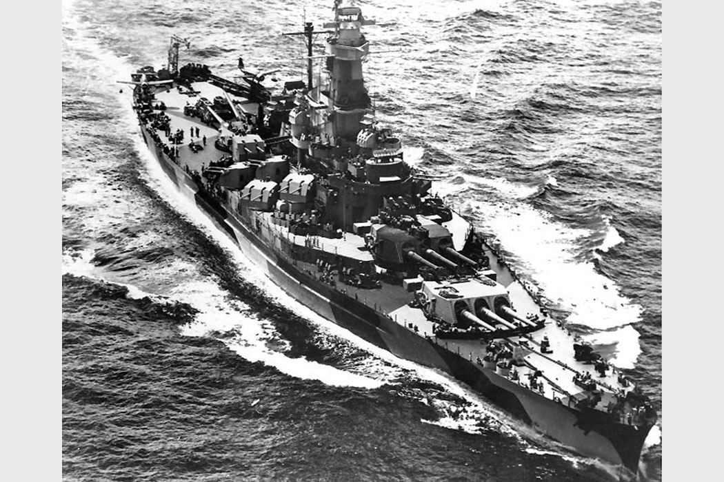 A black-and-white photo of a battleship on water.