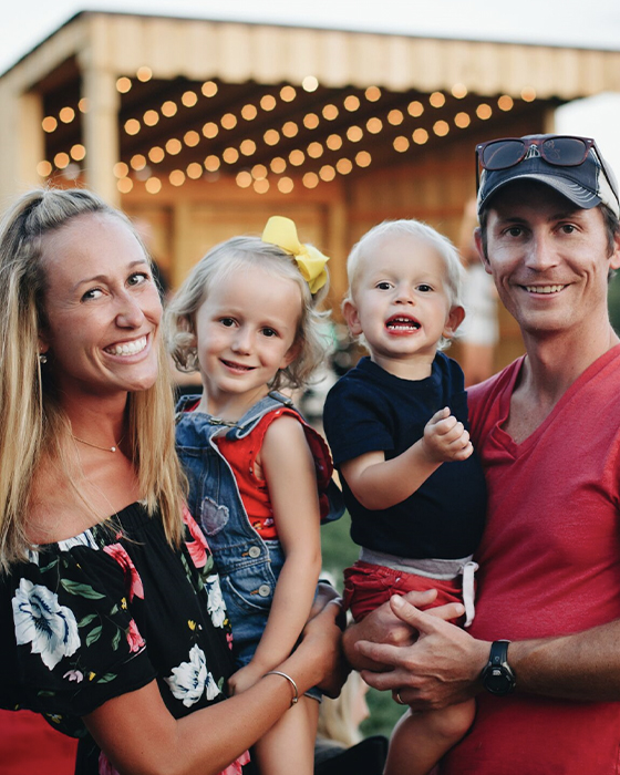 Noah Herron smiles next to wife and two kids 